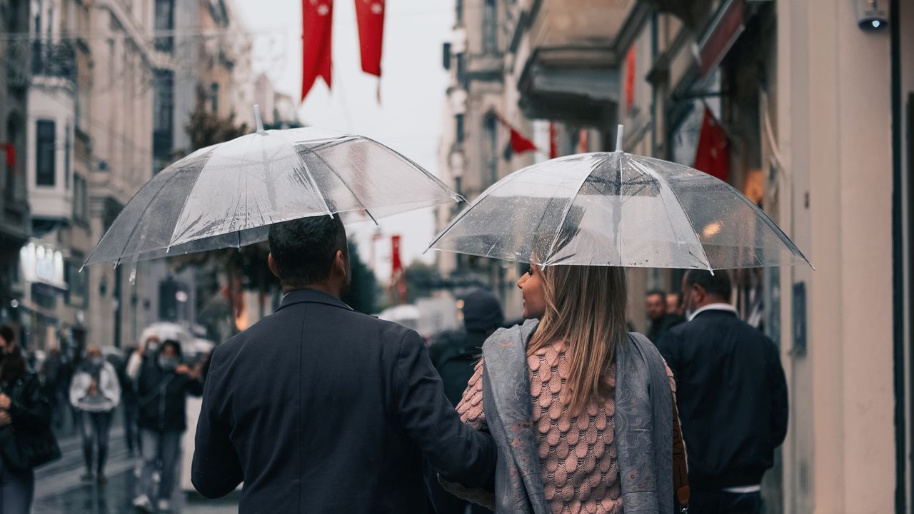 Şeffaf şemsiyeyle yağmurda yürüyen çift